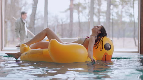 Eine-Erwachsene-Frau-Entspannt-Sich-Im-Pool,-Liegt-Auf-Einem-Aufblasbaren-Schwimmkreis-Wie-Eine-Gelbe-Ente-Und-Meditiert